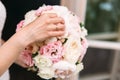 Close-up of a cropped frame, the bride in a white dress is holding her wedding bouquet of peonies, showing flowers to Royalty Free Stock Photo