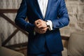 A close-up of a cropped frame of a man puts on a gold watch with a leather belt, is dressed in a stylish suit, a white Royalty Free Stock Photo