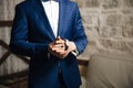 A close-up of a cropped frame of a man puts on a gold watch with a leather belt, is dressed in a stylish suit, a white Royalty Free Stock Photo