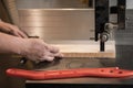 Close-up cropped hands of carpenter professional man hands using panel sizing saw woodworking machines. Pusher on table