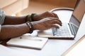 Close up cropped image young black man using laptop.