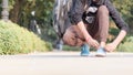 Close up Cropped image of young sportsman athlete man in sports clothing sitting on track and field near playground and tie shoe Royalty Free Stock Photo