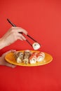 Close up cropped photo of female hand holds makizushi sushi roll served on plate traditional japanese food isolated on Royalty Free Stock Photo