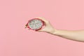 Close up cropped photo of female hold in hand fresh half pitahaya, dragon fruit isolated on pink pastel wall background