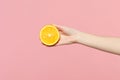 Close up cropped photo of female hold in hand fresh ripe half orange fruit isolated on pink pastel wall background. Copy Royalty Free Stock Photo