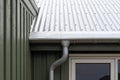 Close up cropped photo of small green house with zinc metallic rain gutter on cornice under rivets roof