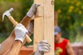 Close up cropped photo of two man holding plank board by hand installing special house hold construction using hammer and nails Royalty Free Stock Photo