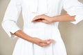 Close up cropped photo of woman`s slim stomach with her hands showing a balance in microflora in a white robe