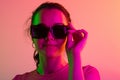 Close-up portrait of young caucasian girl in sunglases isolated over gradient studio background in neon lights Royalty Free Stock Photo
