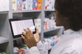 Close-up cropped shot of African American woman doctor or clinical pharmacist using digital tablet while standing in Royalty Free Stock Photo