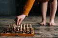 Close-up cropped shot of berefoot legs unrecognizable woman standing near chessboard on wooden vintage floor in dark Royalty Free Stock Photo