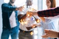 Close-up cropped shot of cheerful business team of young multi-ethnic businesspeople holding Bengal lights and glasses Royalty Free Stock Photo