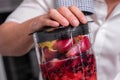 Close up cropped shot of man making smoothie from fresh fruits and berries in professional blender or food processor. Royalty Free Stock Photo