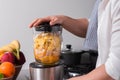 Close up cropped shot of man making smoothie from fresh fruits in professional blender or food processor. Royalty Free Stock Photo
