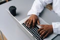 Close-up cropped shot of unrecognizable African-American practitioner male doctor in white coat working typing on laptop Royalty Free Stock Photo