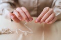 Close-up cropped shot of unrecognizable woman putting thread through eye of needle sitting at table. Royalty Free Stock Photo