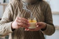 Close-up cropped shot of unrecognizable young woman holding extinguished handmade candle in glass jar near chest. Royalty Free Stock Photo