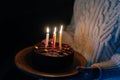 Close-up cropped shot of unrecognizable young woman holding in hands birthday cake with six burning candles in dark room Royalty Free Stock Photo