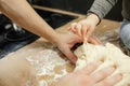 Close up cropped unrecognizable little boy and man hand touch and pinching piece of tasty dough on wooden cutting board