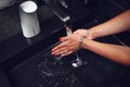 Close-up of cropped unrecognizable woman washing her hands thoroughly under running water on a stylish black ceramic sink