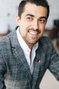 Close-up cropped vertical shot of smiling stylish business man in fashion suit sitting at desk in modern office room Royalty Free Stock Photo