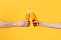 Close up cropped of woman and man two hands horizontal holding lager beer glass bottles and clinking isolated on yellow Royalty Free Stock Photo