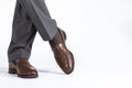 Close- up of Crossed Mens Legs Wearing Brown penny Loafers. Against White Background