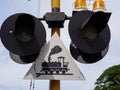 Close up of crossing railroad warning signpost with train symbol, light signal in Thailand in sky background.