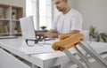 Close up of crutches on background of concentrated man working on laptop in office. Royalty Free Stock Photo