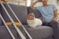 Close up of a crutches and a broken leg in a plaster cast of a woman sitting on a sofa and resting. Royalty Free Stock Photo