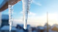 A close-up of a crystal-clear icicle hanging from the edge of a snowy rooftop
