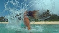CLOSE UP: Crystal clear ocean water flies off playful brunette girl`s hair whipping her head back.