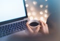 Close-up cup of coffee or tea in hipster girl hands on background relax glitter xmas decoration with an open laptop in home atmosp Royalty Free Stock Photo