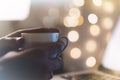 Close-up cup of coffee or tea in hipster girl hands on background relax glitter xmas decoration with an open laptop in home Royalty Free Stock Photo