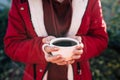 Close up of cup of coffee in woman's hands. Unrecognizable female holds hot mug of drink, standing in garden. Royalty Free Stock Photo