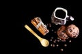 Close-up cup of espresso coffee, milk and spoon, round crunchy chocolate cookies with coffee beans, sticks of cinnamon on a black