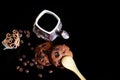 Close-up cup of espresso coffee, spoon, round crunchy chocolate cookies with coffee beans, sticks of cinnamon on a black backgroun