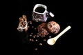 Close-up cup of espresso coffee, spoon, round crunchy chocolate cookies with coffee beans, sticks of cinnamon on a black backgroun