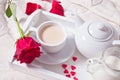 Close up of cup of tea with red rose on the white tray