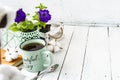 Close-up of a cup of tea on a wooden white table with blurred background, front blur. Still life with flower, book, teaspoon, Royalty Free Stock Photo