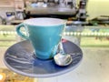 Close up of a cup of turquoise coffee on a saucer and with the steel spoon served on the glass counter of an Italian bar