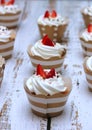 Close-up cupcakes with whipped eggs cream decorated fresh strawberry and chocolate balls on old white wooden table background Royalty Free Stock Photo