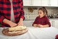 Close-up of a curious adorable little girl in checkered dress looking at her mother`s hands kneading dough for Christmas cookies Royalty Free Stock Photo