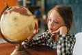 Close-up of curious child girl spinning small globe with interest, looking at countries of world. Royalty Free Stock Photo