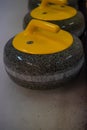 Close-up of a curling stone with a yellow handle stands on ice Royalty Free Stock Photo