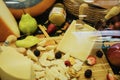 Close-up of cut Cheese with knife on wooden board and fruit on showcase on counter at store, real scene in food market Royalty Free Stock Photo