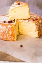 Close up of cut slice of French or German soft cheese with orange rind with mold, creamy texture, red pepper corns Royalty Free Stock Photo