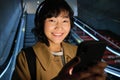Close up of cute asian girl in headphones, picks song to listen while commuting, going down escalator to metro, smiling