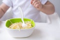 close up cute baby girl eating spaghetti pasta sitting in baby chair on white kitchen Royalty Free Stock Photo