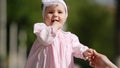 Close-up of the cute baby-girl playing and dancing in the park.